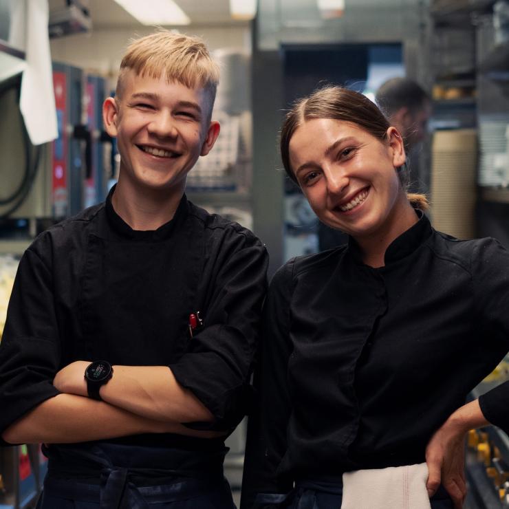 Two young chefs laughing into the camera