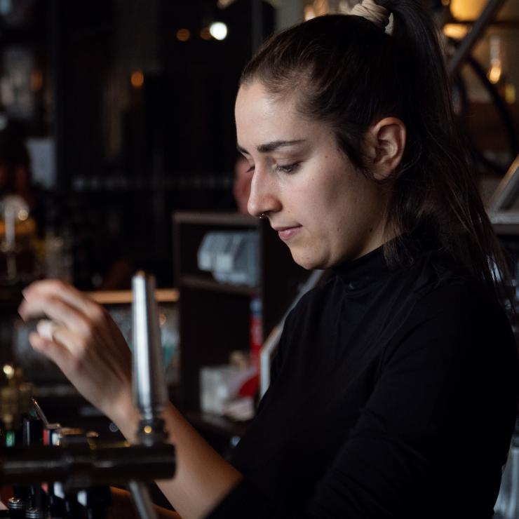 Bar employee tapping beer